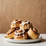 Golden baked frozen cinnamon buns with icing on a white plate in a cozy kitchen setting