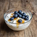 Greek yogurt with fresh blueberries and honey in a glass bowl